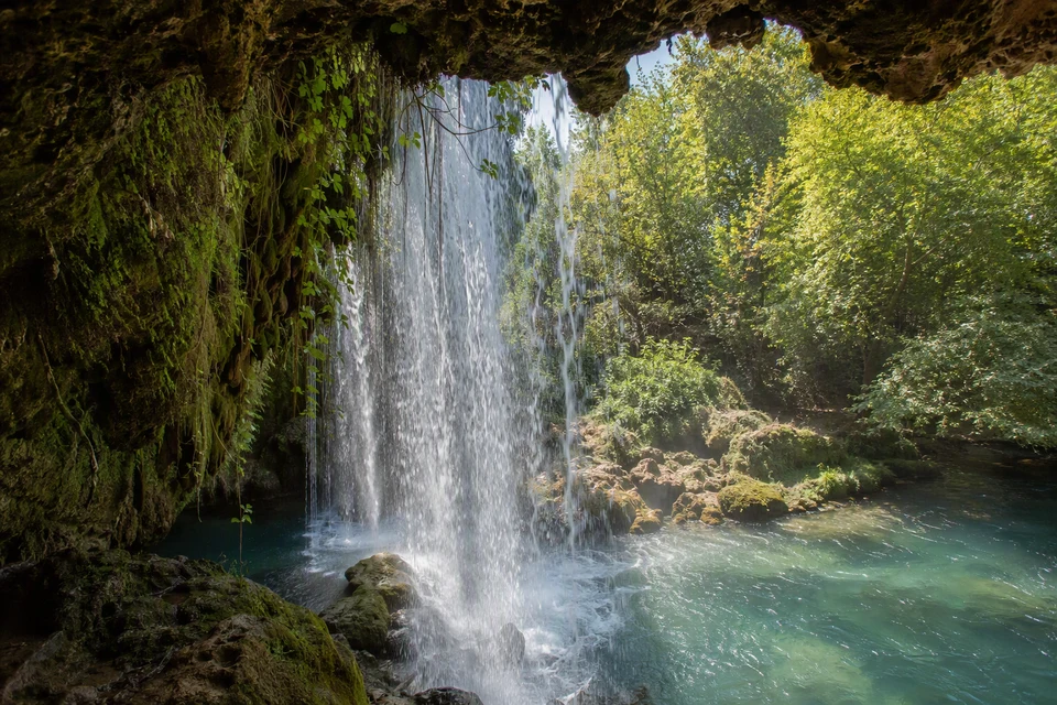 Water curtain seen through the mossy rock recess behind Upper Duden Waterfall, AI recreation